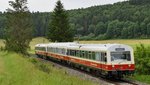 Ein alter Triebwagenzug fährt durch die grüne Landschaft